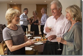 Woman Serving Hors D'oeuvres To Her Guests At A Dinner Party